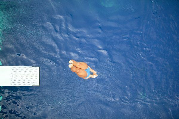 female springboard diver diving into the swimming pool
