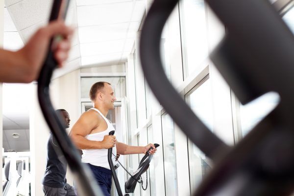 Two young men running on treadmill in gym
