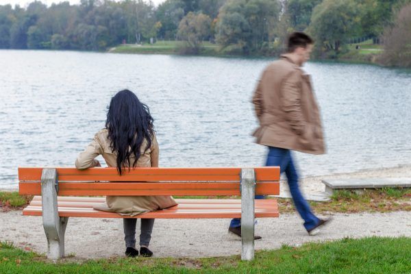 Eine junge Frau sitzt nachdenklich auf einer Parkbank