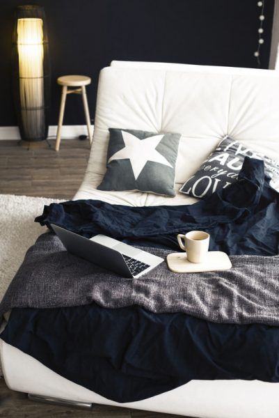 Cozy couch with blanket, coffee and laptop in modern interior in black and white colors