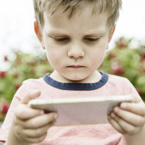 Junge schaut im Garten auf ein Smartphone,Köln, Nordrhein-Westfalen, Deutschland