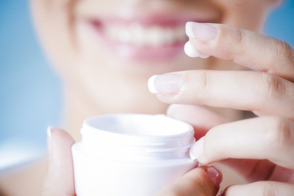Hands of a woman about to apply face cream.