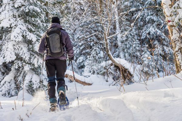Young man snowshoeing in winter, in the Quebec eastern townships region, Canada