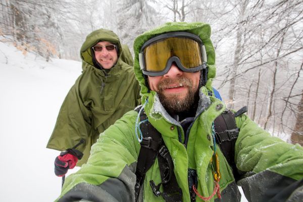 Man is hiking in winter forest on cloudy day