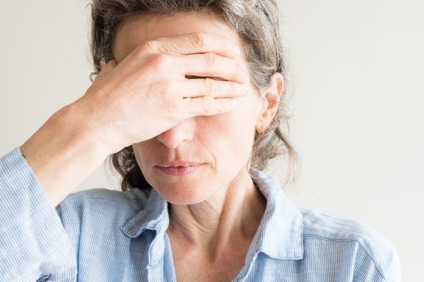 Close up of middle aged woman with hand coverying eyes