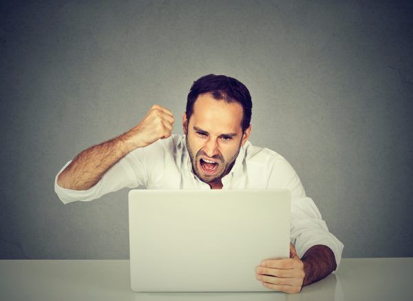 Portrait angry business man working on the laptop. Negative human emotion face expression