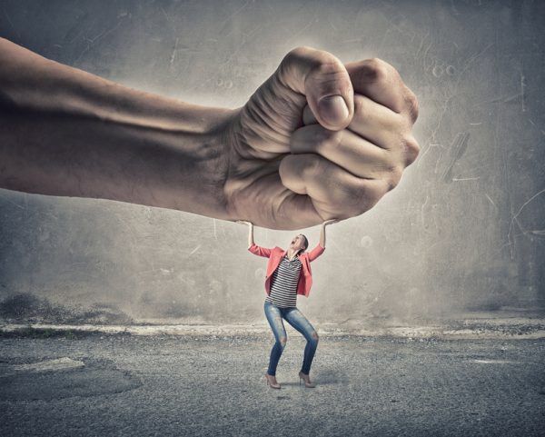 Small woman under pressure of big human hand