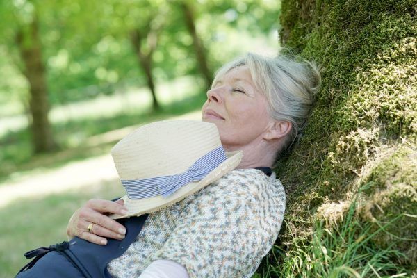 Senior woman relaxing in garden by tree