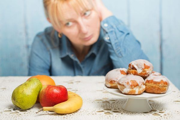 Woman choosing between fruit and sweets