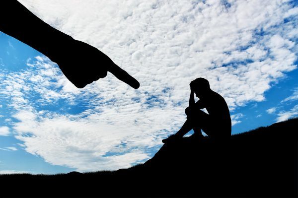 Child abuse and bullying. Silhouette of sad boy and hand of an adult man pointing at him