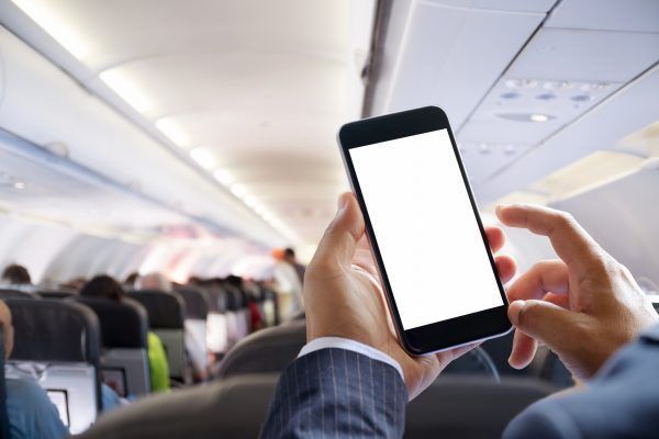 Airplane passenger using smart phone on plane. Businessman touching blank screen mobile phone at airplane. for graphics display montage.