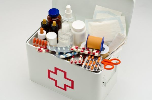 Open first aid box filled with medical supplies in white background