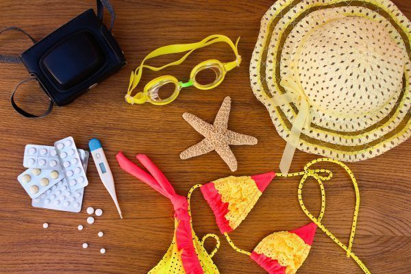 Summer beach accessories and medicine on the table. The concept of medication required in the journey