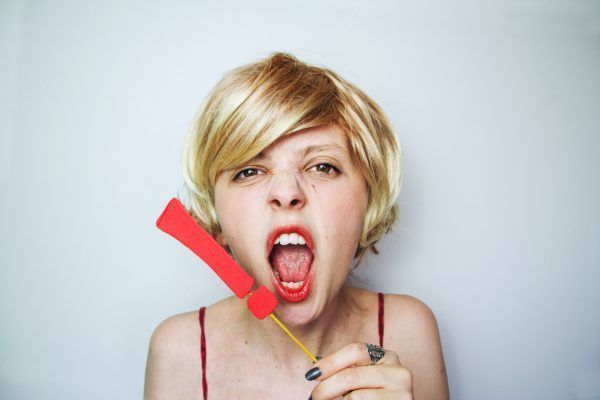 Mujer joven y rubia gritando con un signo de exclamacin junto a su cara