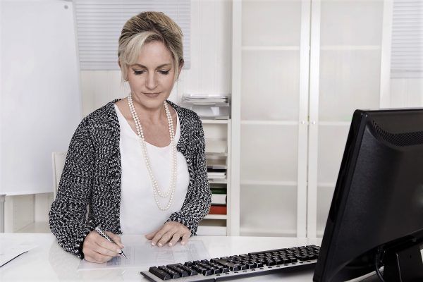 ltere Frau sitzend am Schreibtisch