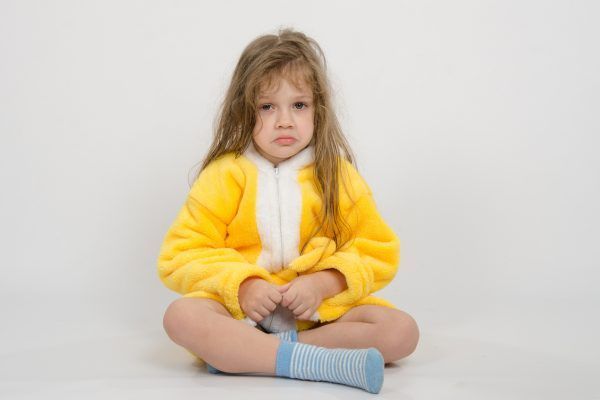 Four-year girl with wet hair in a bathrobe on a light background