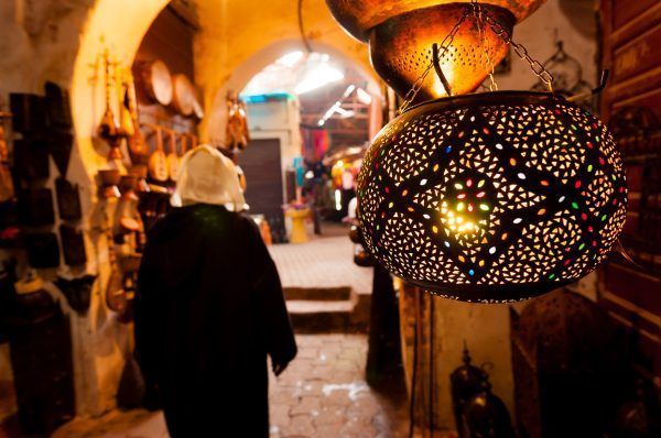 A woman walks past a lantern shop in a Marrakech souk.