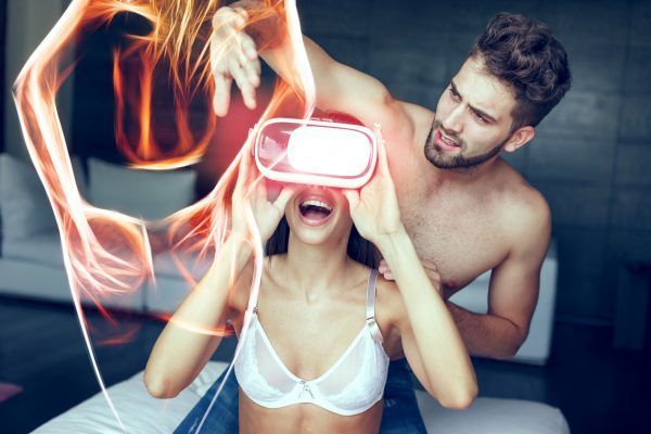 Young couple playing with VR headset at home, excited woman in bra, fiery virtual girl silhouette