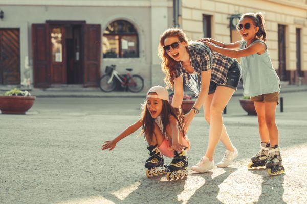Mother plays with her daughters on street in neighborhood.They drive roller blades .Family concept.