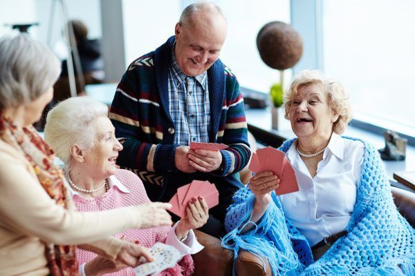 Group of positive seniors playing cards