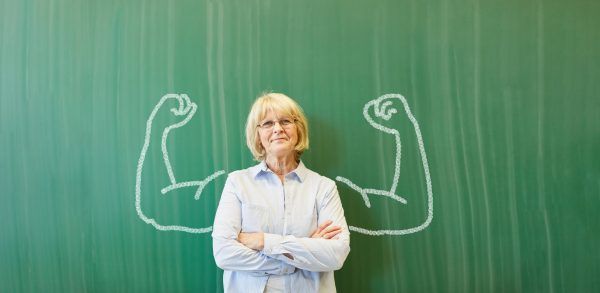 Alte starke Frau als Lehrer vor Tafel mit Muskeln in der Schule