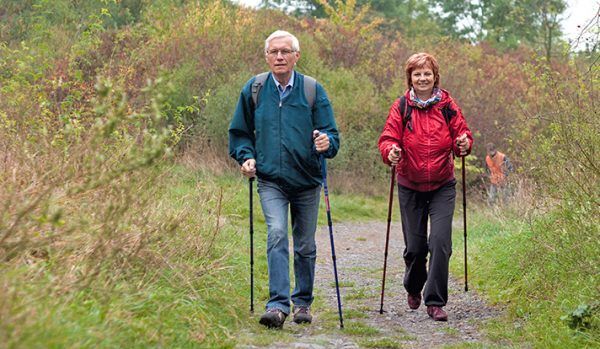 Senior couple Nordic walking on rocky trail in the nature.