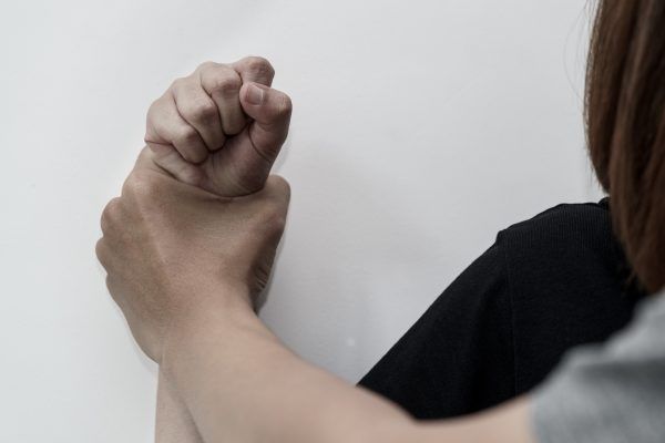 Man hand oppressing or pressing woman wrist on the wall - woman violence concept