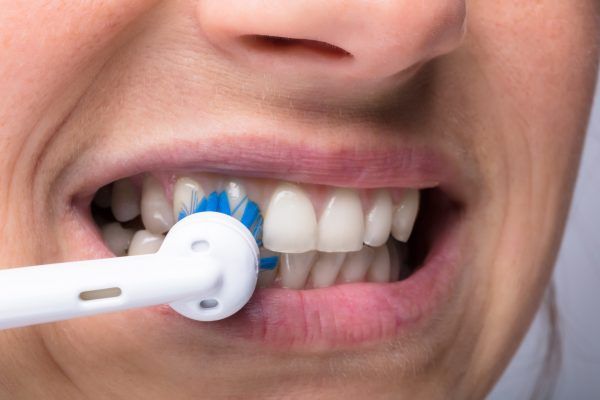 Close-up Of A Woman's Teeth With Electrical Toothbrush