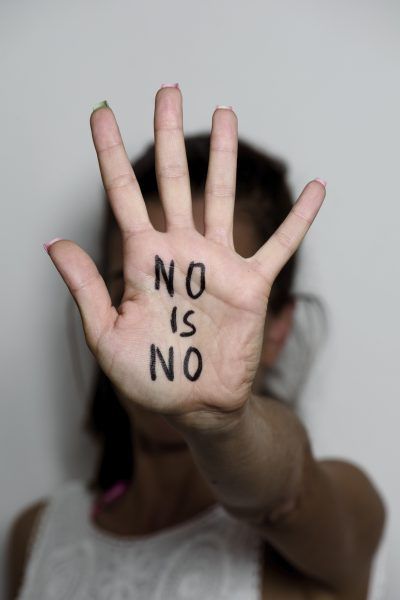 closeup of the hand of a young caucasian woman in front of her face with the text no is no written in her palm